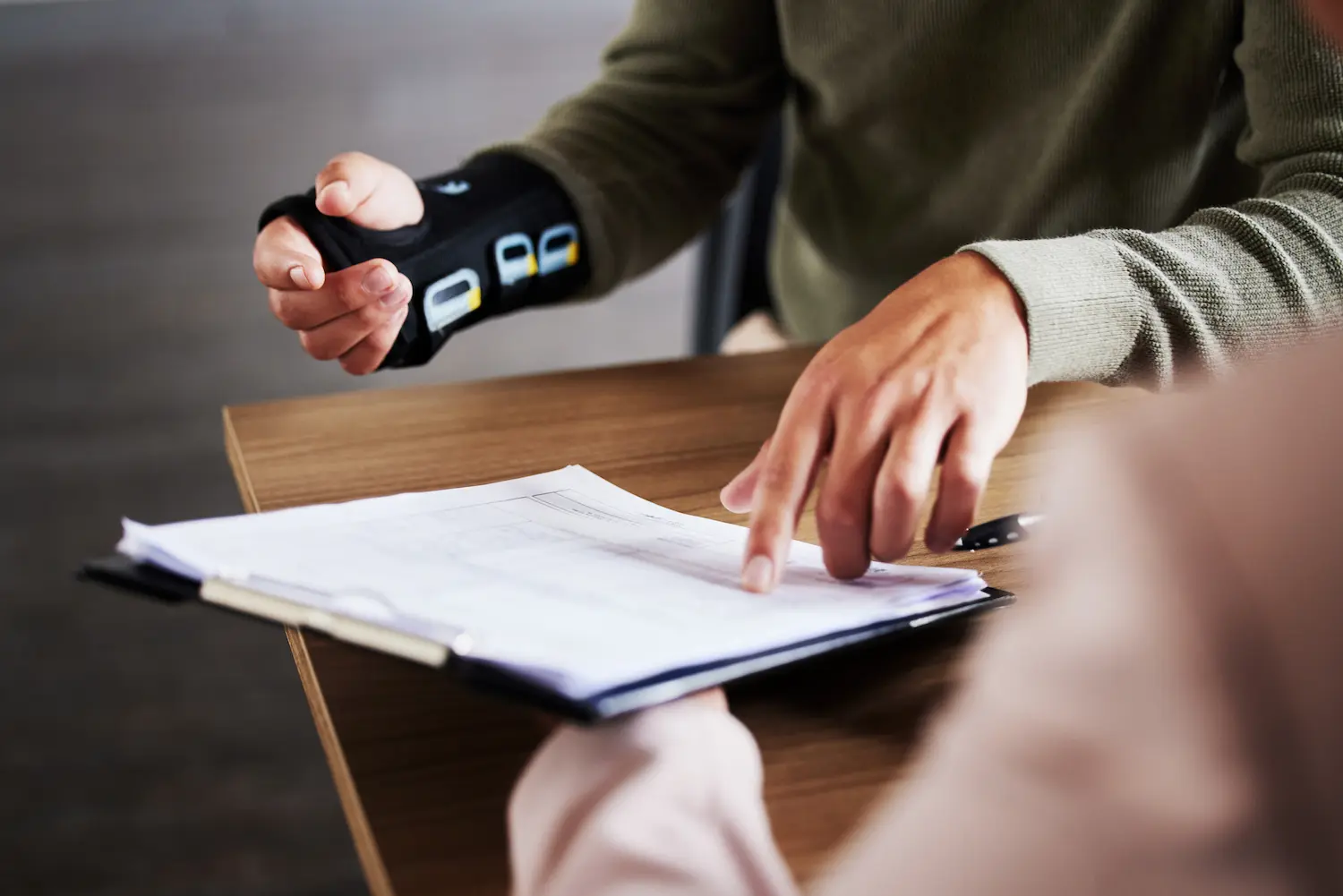 Injured hand in brace pointing at legal documents with personal injury lawyers in Hillsboro Oregon