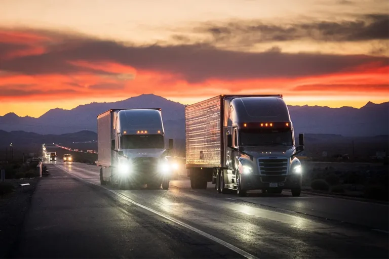 Semi trucks on a freeway at sunset